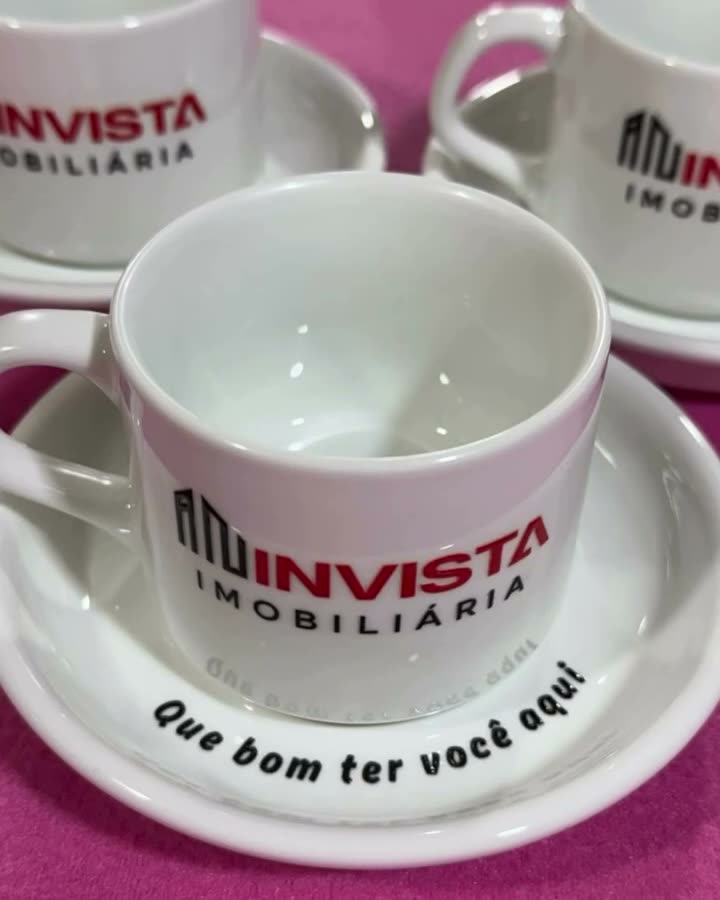 Xícaras com pires com a marca de uma imobiliária e a frase Que bom ter você aqui